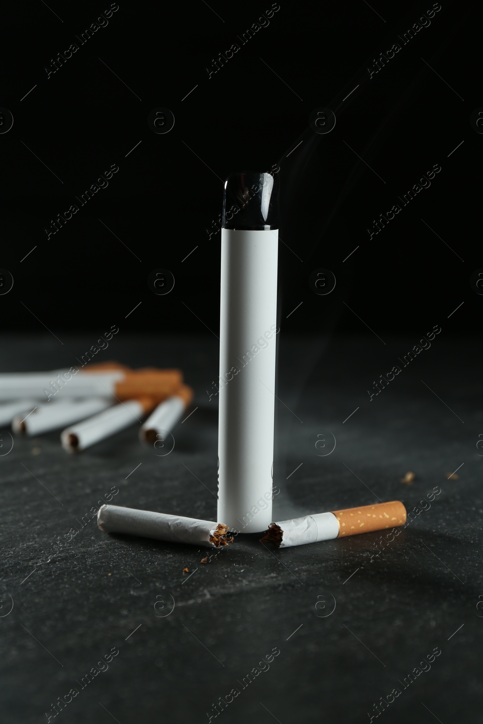 Photo of Electronic smoking device and cigarettes on black table