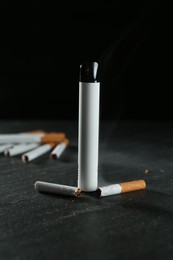 Photo of Electronic smoking device and cigarettes on black table