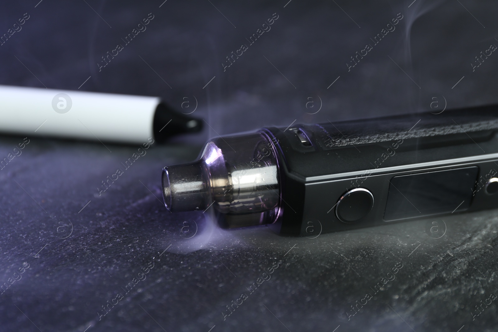 Modern electronic smoking devices on black table, closeup Photo of Modern electronic smoking devices on black table, closeup