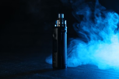 Photo of Electronic smoking device on black table in blue light