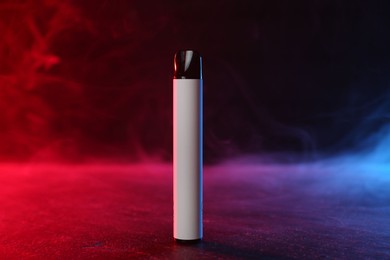 Photo of Electronic smoking device on black table in red light