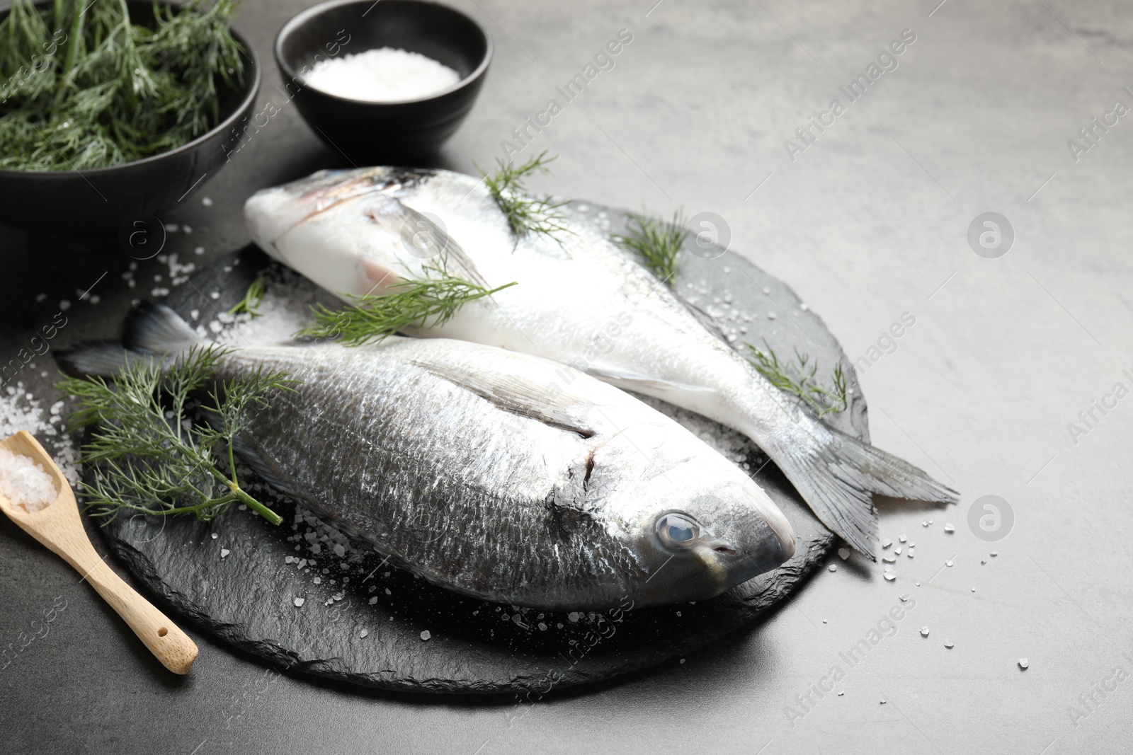 Organic seafood. Fresh raw dourade fish, salt and dill on grey table, closeup Photo of Organic seafood. Fresh raw dourade fish, salt and dill on grey table, closeup