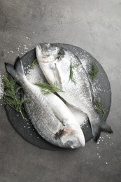 Photo of Organic seafood. Fresh raw dourade fish, salt and dill on grey table, flat lay
