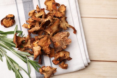 Photo of Dried chanterelle mushrooms and rosemary on light wooden table, top view