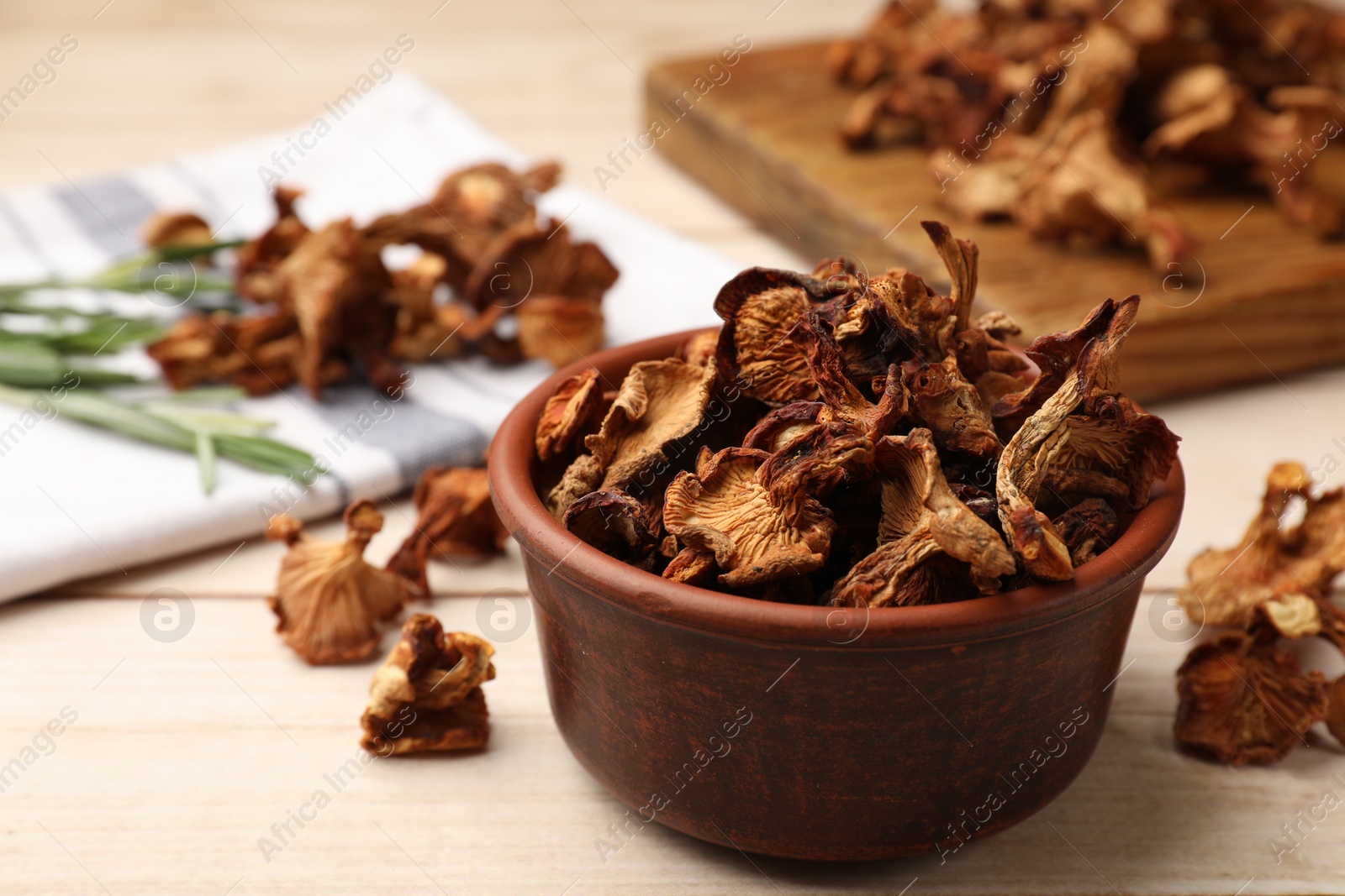 Dried chanterelle mushrooms in bowl on light wooden table, closeup Photo of Dried chanterelle mushrooms in bowl on light wooden table, closeup