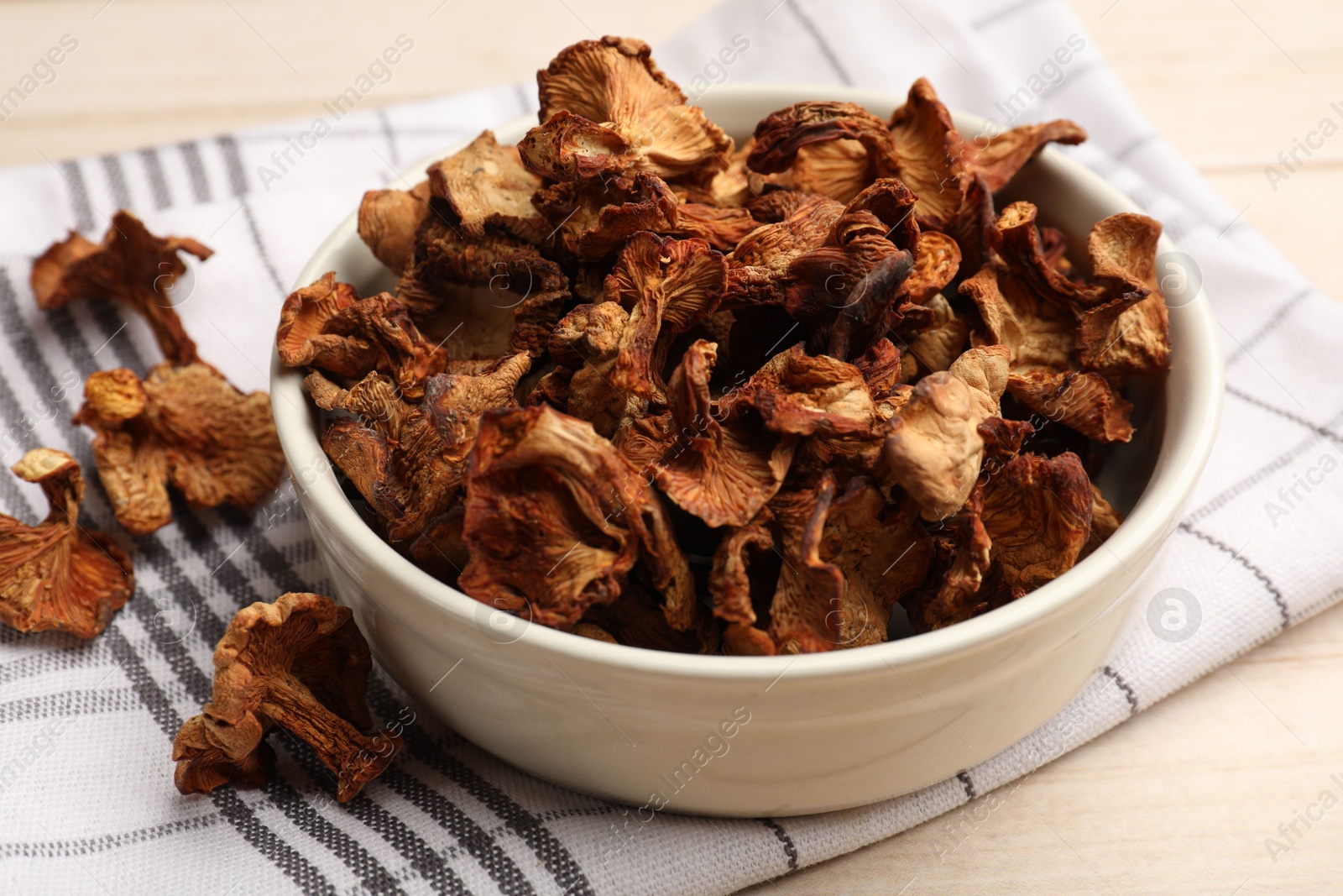 Dried chanterelle mushrooms in bowl on light wooden table, closeup Photo of Dried chanterelle mushrooms in bowl on light wooden table, closeup