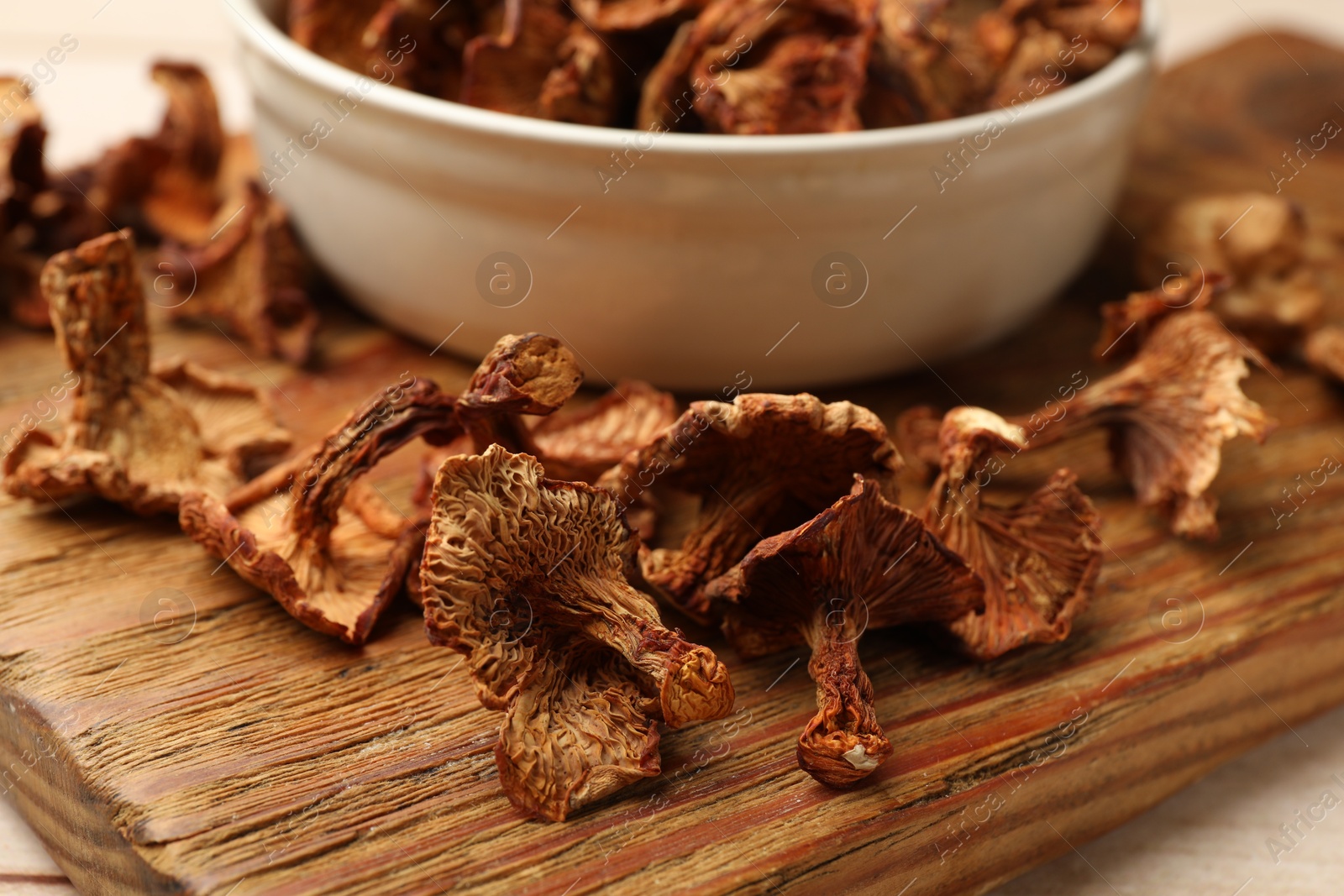 Dried chanterelle mushrooms in bowl on light wooden table, closeup Photo of Dried chanterelle mushrooms in bowl on light wooden table, closeup