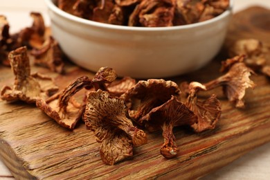 Photo of Dried chanterelle mushrooms in bowl on light wooden table, closeup