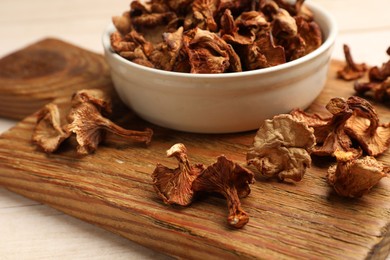 Photo of Dried chanterelle mushrooms in bowl on light wooden table, closeup