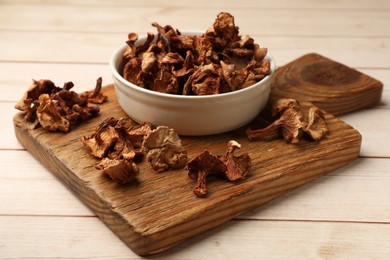 Photo of Dried chanterelle mushrooms in bowl on light wooden table, closeup