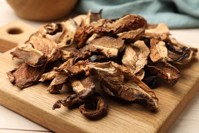 Photo of Pieces of dried mushrooms on light wooden table, closeup