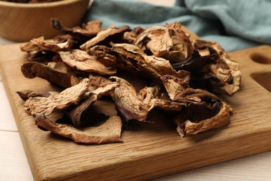 Photo of Pieces of dried mushrooms on light wooden table, closeup