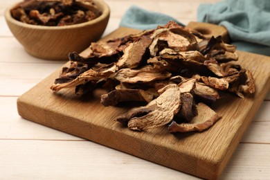 Photo of Pieces of dried mushrooms on light wooden table, closeup