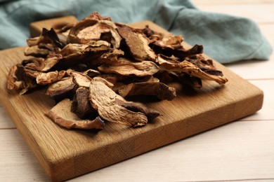 Photo of Pieces of dried mushrooms on light wooden table, closeup