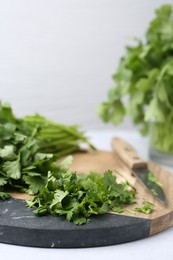 Photo of Fresh green cilantro and knife on light table, closeup