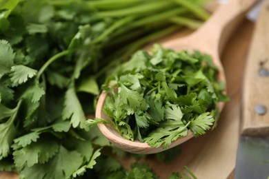 Photo of Fresh green cilantro and wooden spoon on table, closeup