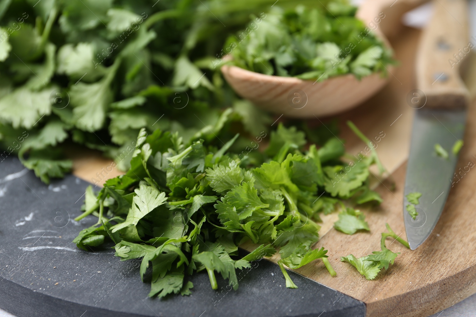 Photo of Fresh green cilantro, knife and wooden spoon on table, closeup