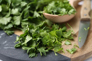 Photo of Fresh green cilantro, knife and wooden spoon on table, closeup