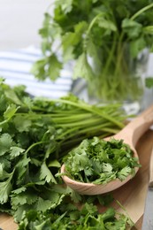 Photo of Fresh green cilantro and wooden spoon on table, closeup