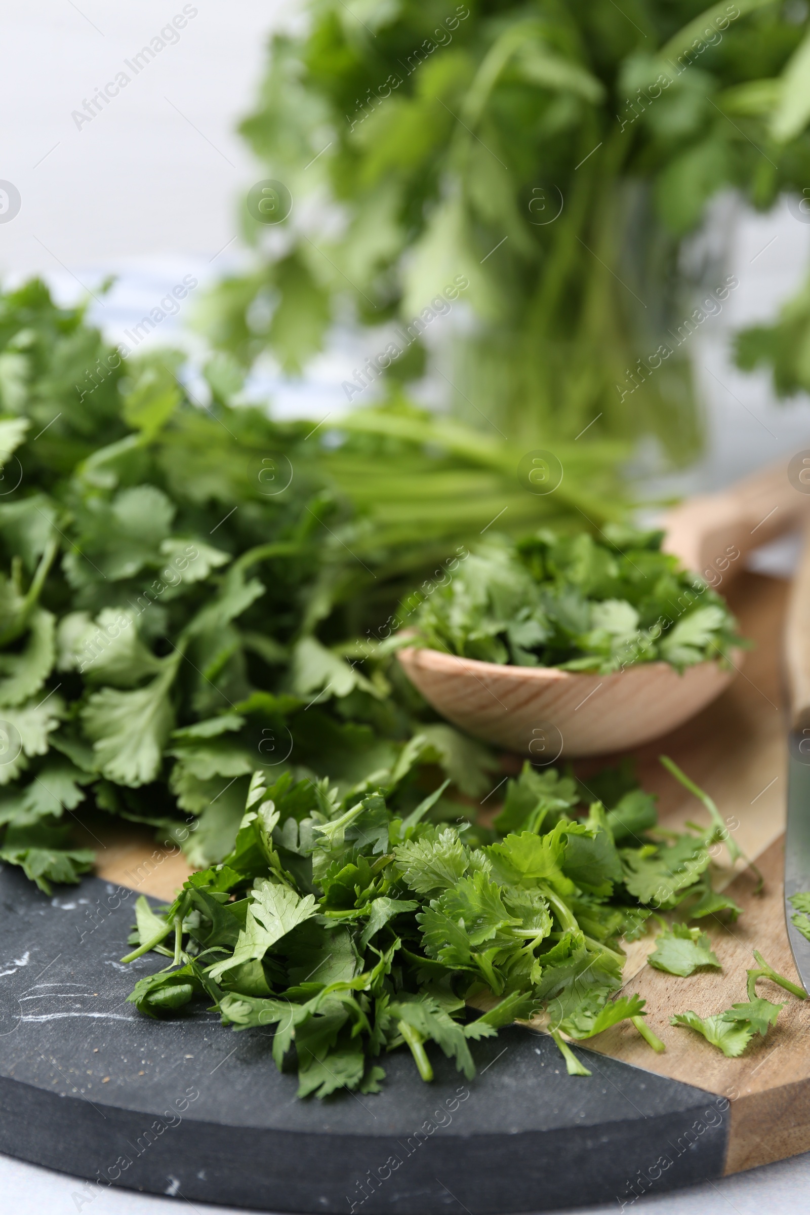 Photo of Fresh green cilantro and wooden spoon on table, closeup