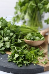 Photo of Fresh green cilantro and wooden spoon on table, closeup