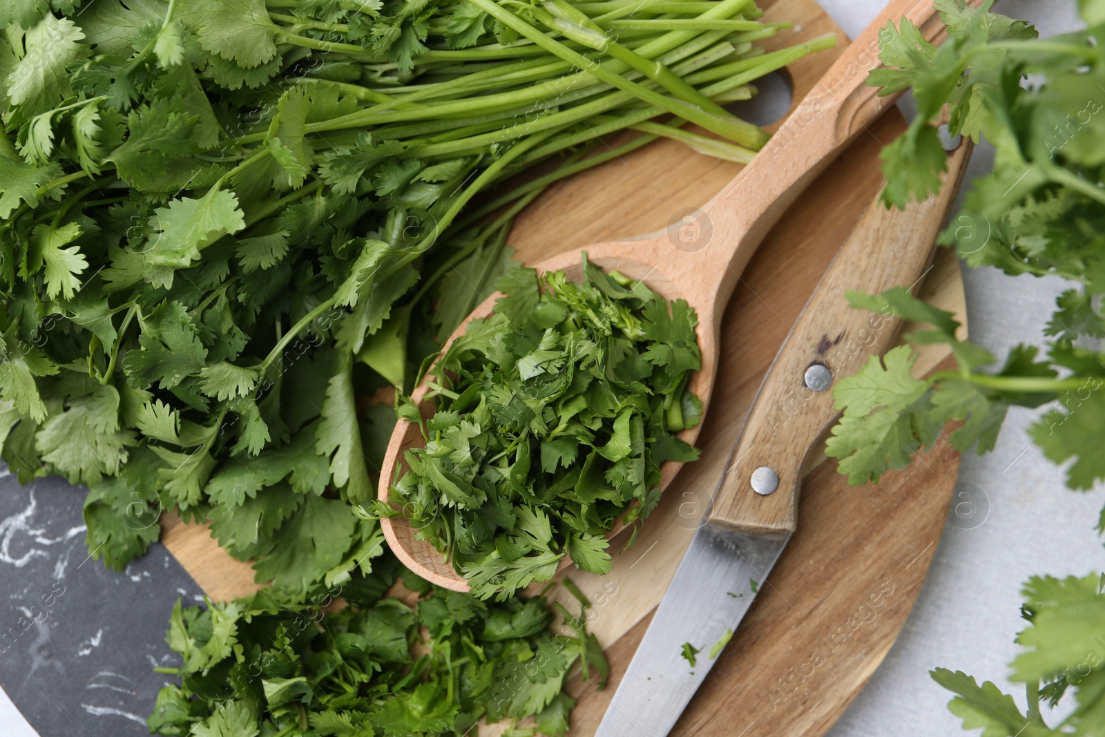 Photo of Fresh green cilantro and knife on light table, top view
