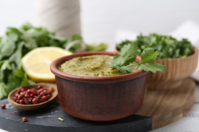 Photo of Tasty sauce with cilantro and other ingredients on table, closeup