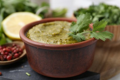 Photo of Tasty sauce with cilantro and other ingredients on table, closeup