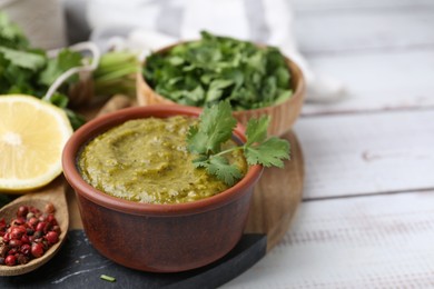 Photo of Tasty sauce with cilantro and other ingredients on white wooden table, closeup. Space for text