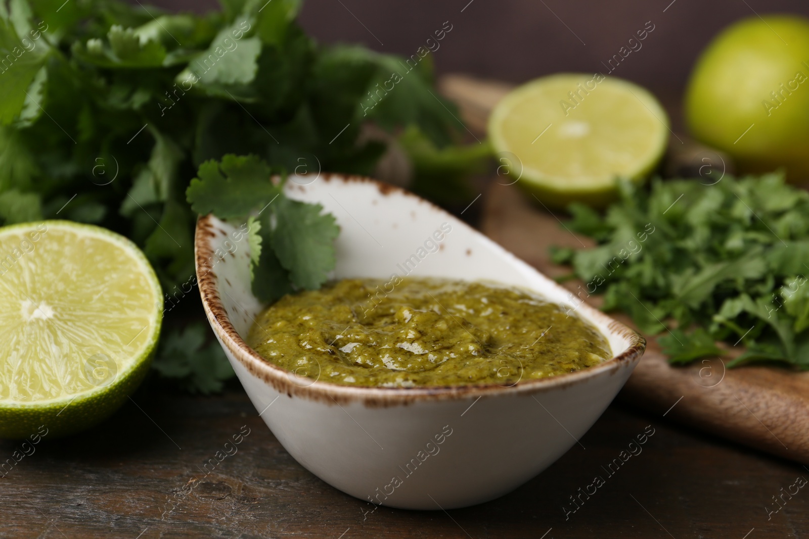 Tasty sauce with cilantro and limes on wooden table, closeup Photo of Tasty sauce with cilantro and limes on wooden table, closeup