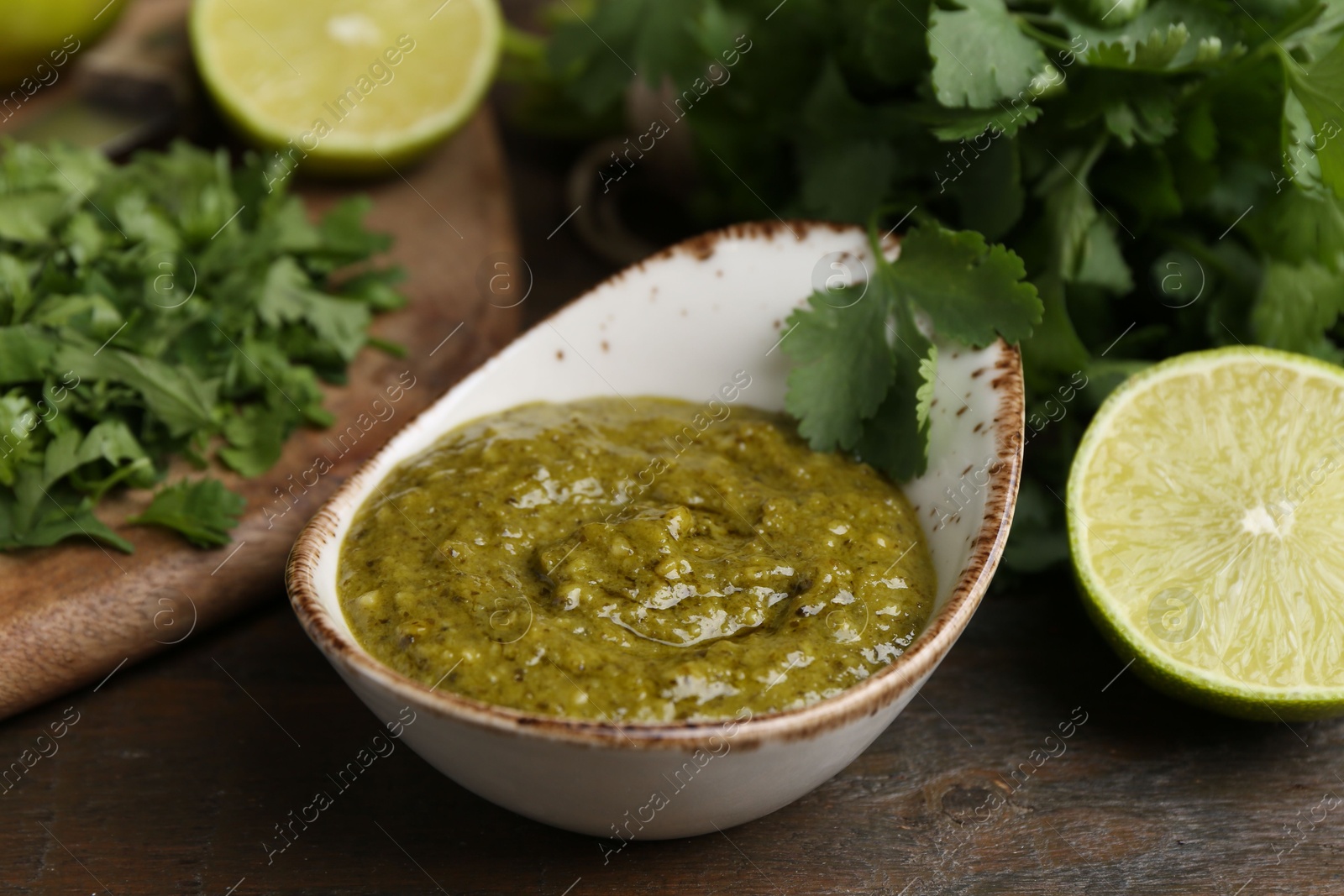 Tasty sauce with cilantro and limes on wooden table, closeup Photo of Tasty sauce with cilantro and limes on wooden table, closeup