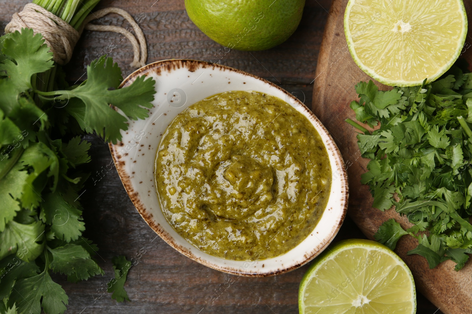 Tasty sauce with cilantro and limes on wooden table, flat lay Photo of Tasty sauce with cilantro and limes on wooden table, flat lay