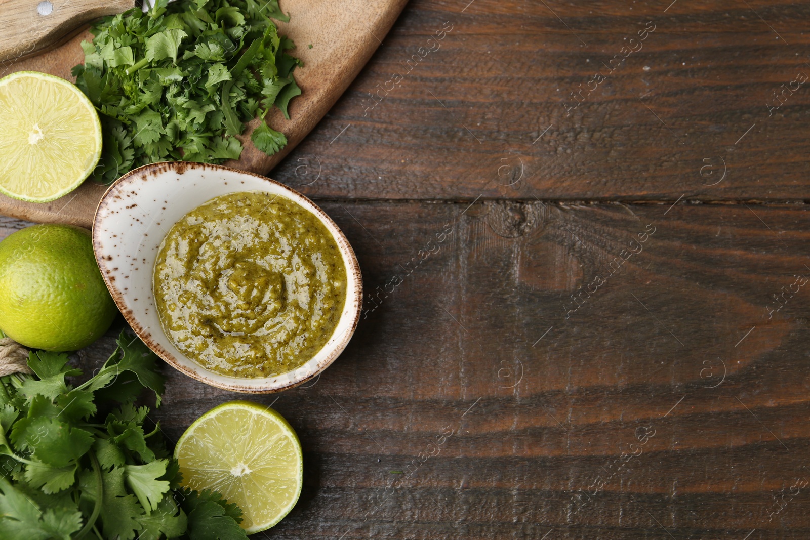 Tasty sauce with cilantro and limes on wooden table, flat lay. Space for text Photo of Tasty sauce with cilantro and limes on wooden table, flat lay. Space for text