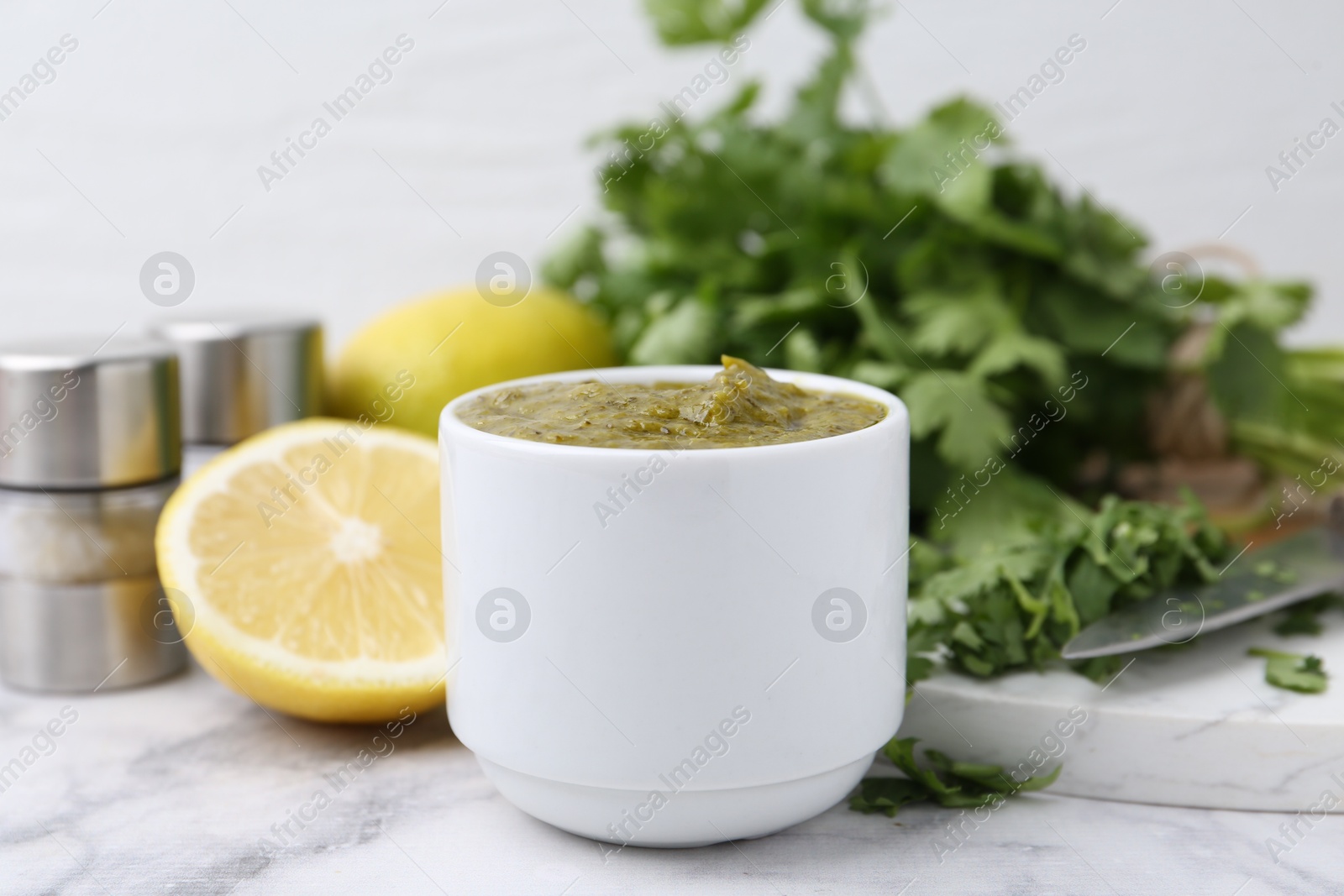 Tasty sauce with cilantro and other ingredients on white marble table, closeup Photo of Tasty sauce with cilantro and other ingredients on white marble table, closeup
