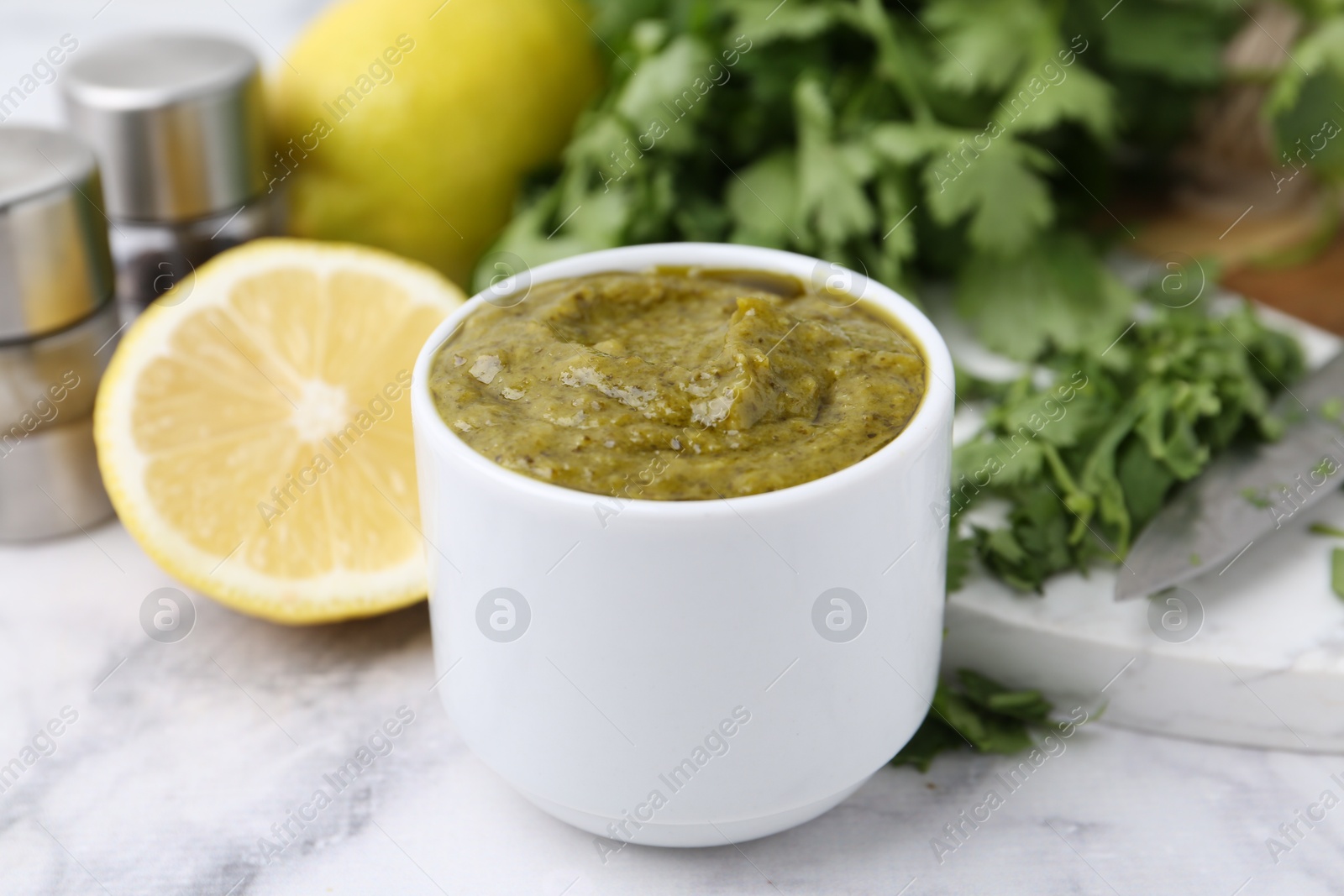 Tasty sauce with cilantro and other ingredients on white marble table, closeup Photo of Tasty sauce with cilantro and other ingredients on white marble table, closeup