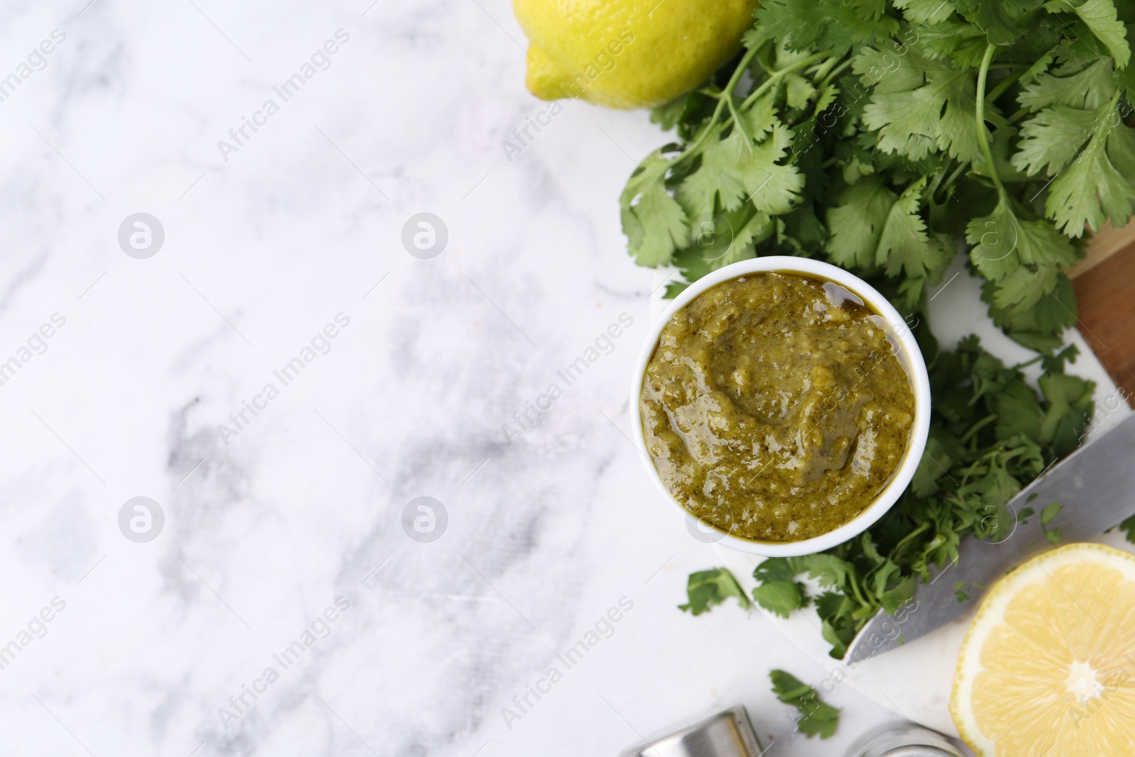 Tasty sauce with cilantro and lemons on white marble table, flat lay. Space for text Photo of Tasty sauce with cilantro and lemons on white marble table, flat lay. Space for text