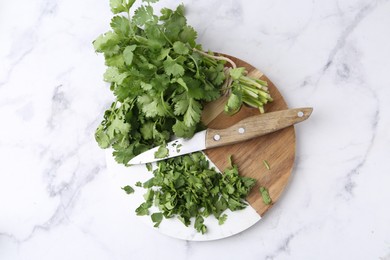 Photo of Fresh green cilantro and knife on white marble table, top view