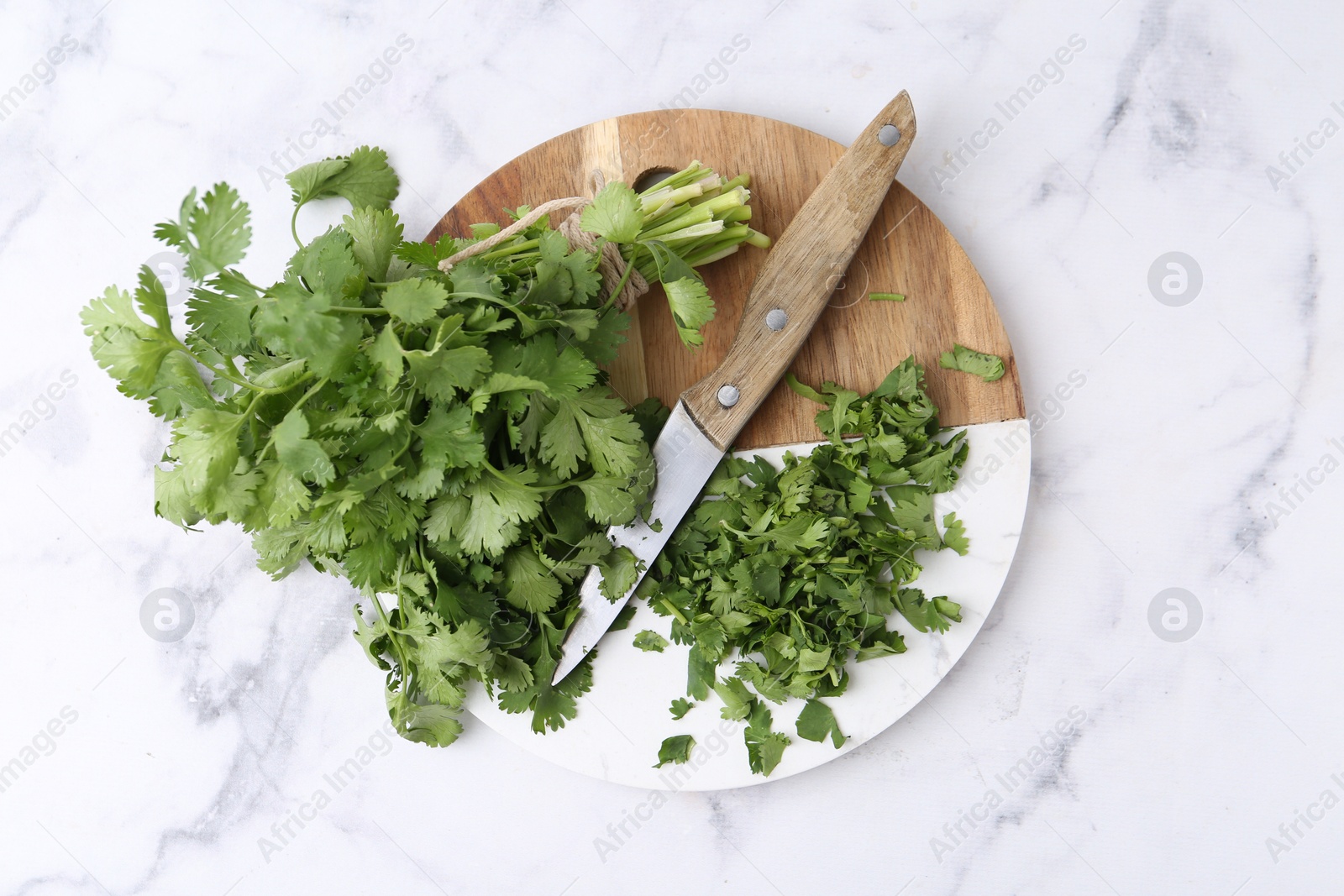 Photo of Fresh green cilantro and knife on white marble table, top view