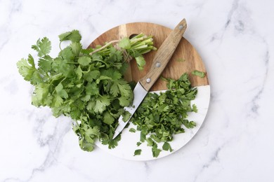 Photo of Fresh green cilantro and knife on white marble table, top view