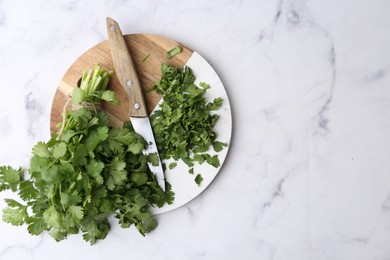 Photo of Fresh green cilantro and knife on white marble table, top view. Space for text