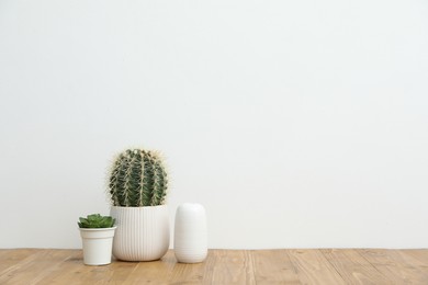 Photo of Floral decor and vase on wooden table near white wall indoors, space for text