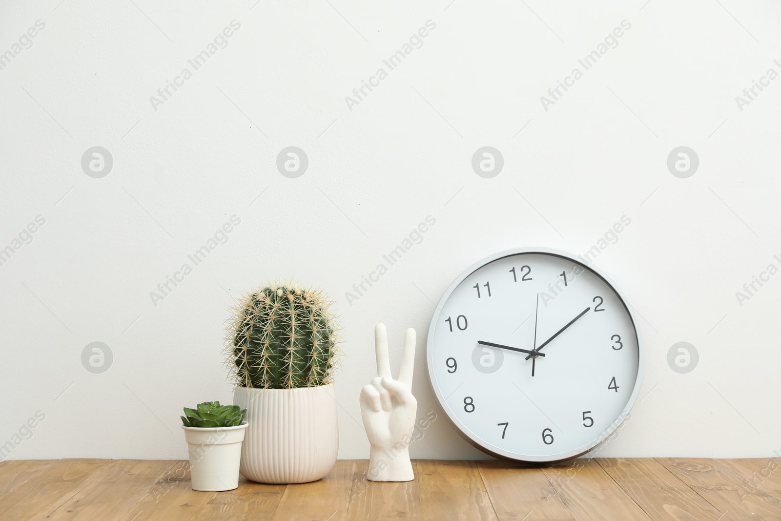 Different decor and round clock on wooden table near white wall indoors Photo of Different decor and round clock on wooden table near white wall indoors