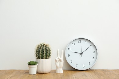 Photo of Different decor and round clock on wooden table near white wall indoors