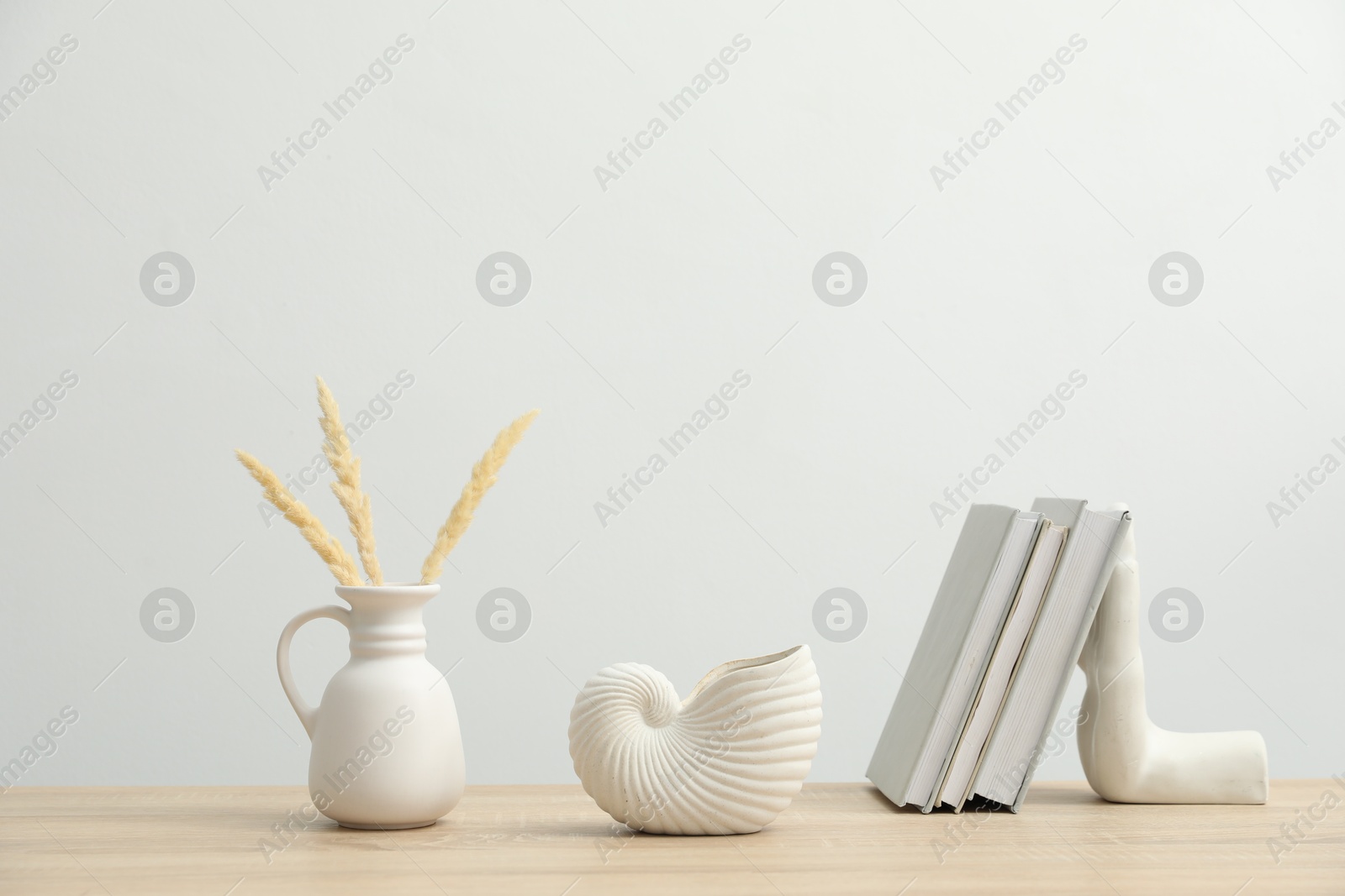 Photo of Different decor and books on wooden table near white wall indoors