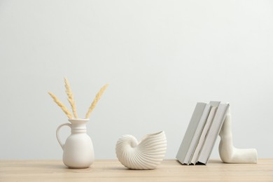 Photo of Different decor and books on wooden table near white wall indoors