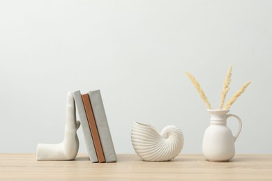 Photo of Different decor and books on wooden table near white wall indoors