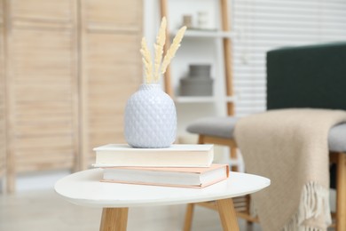 Photo of Dried spikes in vase and books on white table indoors