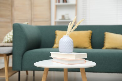 Photo of Dried spikes in vase and books on white table indoors