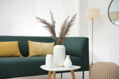 Photo of Dried reeds and vases on white table indoors