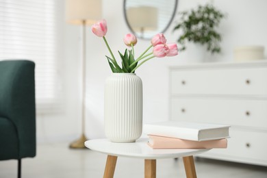 Photo of Beautiful tulip flowers in vase and books on white table indoors